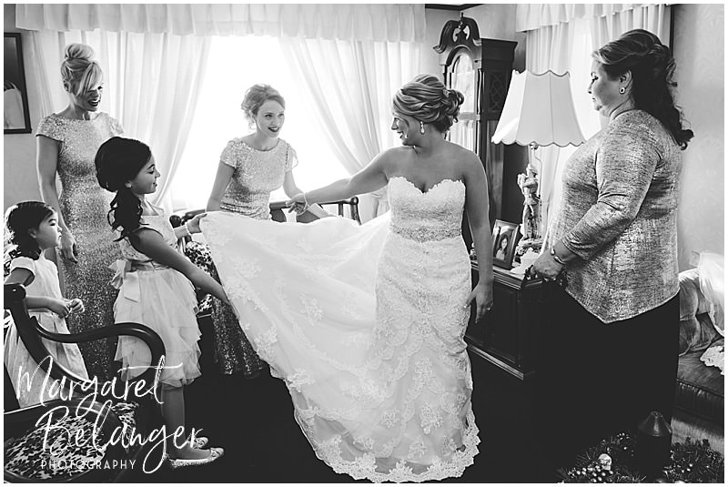 black and white photo of bridesmaids fixing bride's train