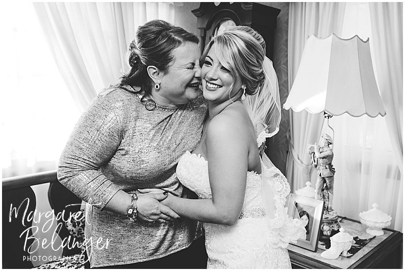 black & white photo of bride and mom snuggling before winter wedding ceremony