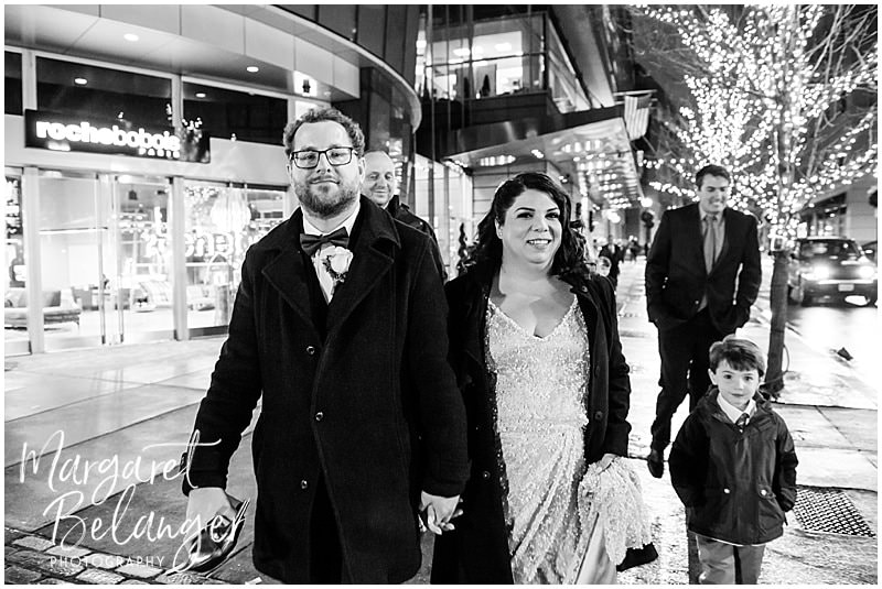 black and white photo of the bride and groom walking through Downtown Crossing in Boston