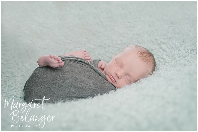 Lowell newborn session, baby in gray swaddle on aqua blanket