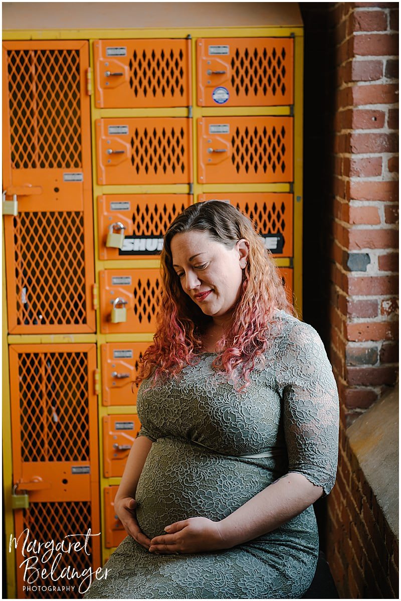 Mill No. 5 Lowell maternity session, mom-to-be sitting near orange lockers