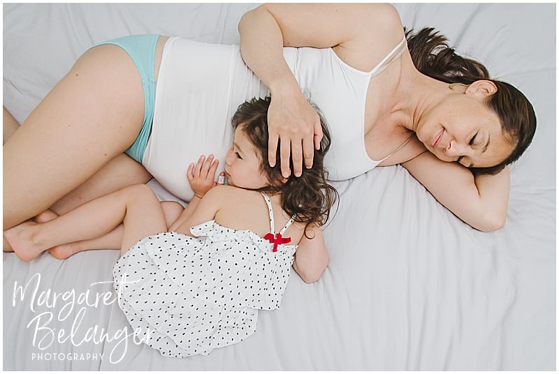 South End maternity session, mama-to-be and daughter snuggling on bed