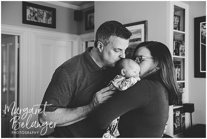 South Shore newborn session, mom holding baby girl on her shoulder and dad kisses her