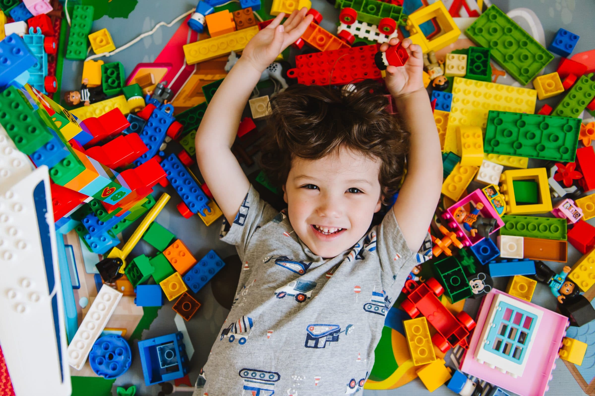 Boy lying down with colorful legos all around his head