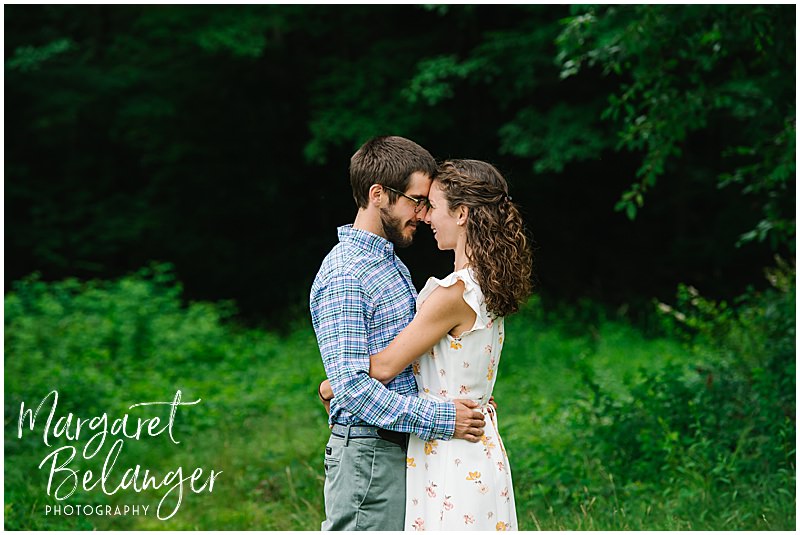 Couple hugging, forehead to forehead, in the greenery at Waterville Valley