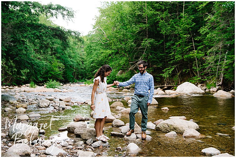 Couple walks on rocks across the river at Waterville Valley Resort