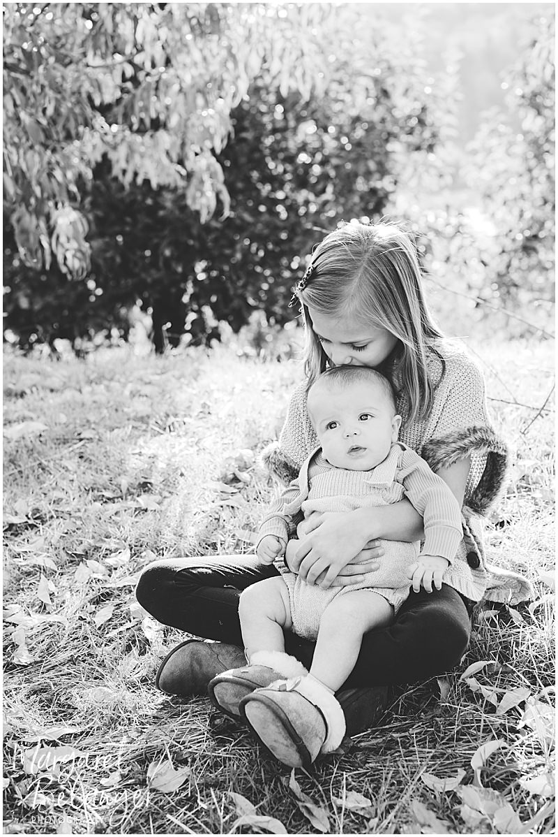 B&W photo of a girl holding her baby brother on her lap in an orchard, Boston Hill Farm, Andover
