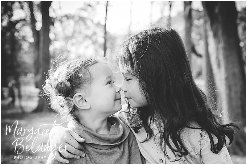 Black and white photo of two sisters touching noses during their fall family session at Endicott Park in Danvers.