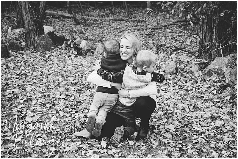 Black and white photo of Mom hugging her two son in the leaves at their Minute Man National Park fall family session