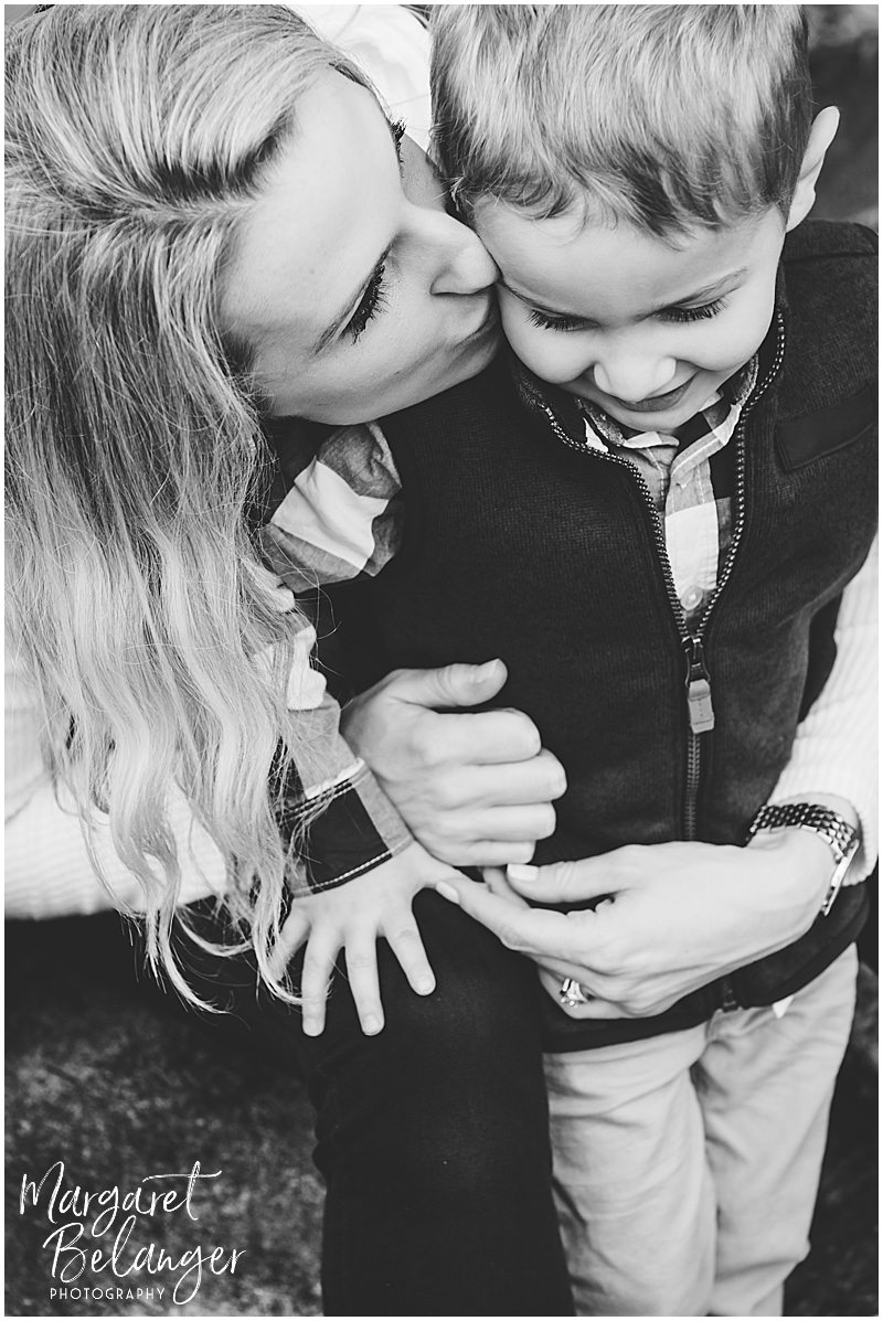 Black and white photo of mom kissing her son on the cheek at their Minute Man National Park fall family session