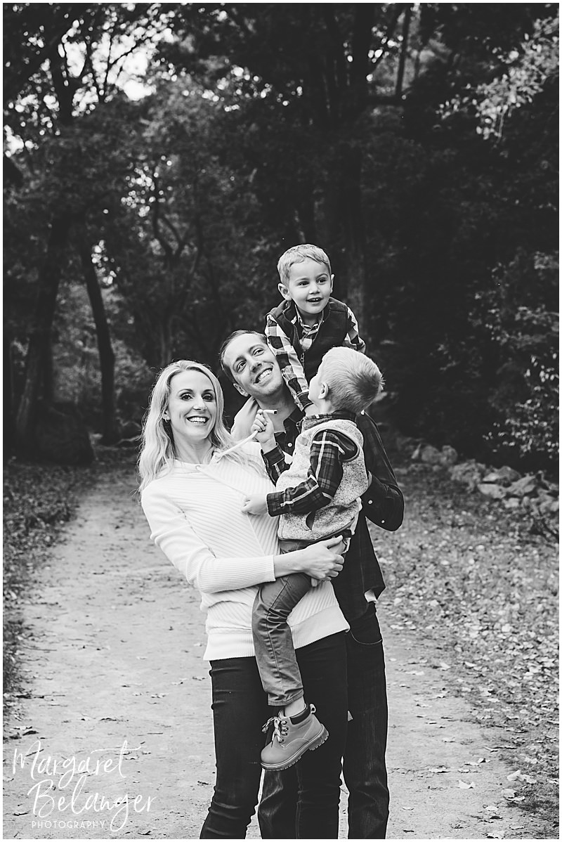 Black and white family photo of mom and dad holding their two sons during their Minute Man National Park family session in Lincoln.