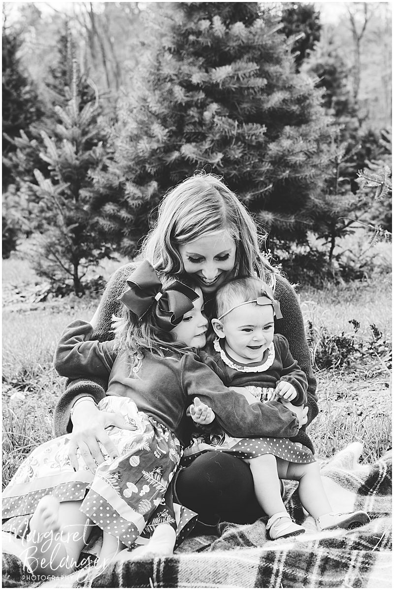 Black and white photo of mom snuggling her two daughters during their fall family session at Mistletoe Christmas Tree Farm in Stow.