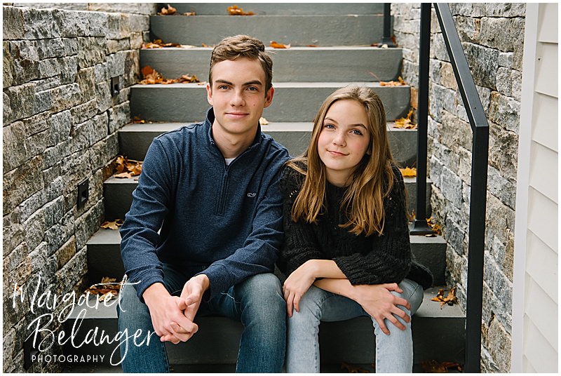 Teenage siblings sitting next to each other on stairs during their fall family session in Newton.