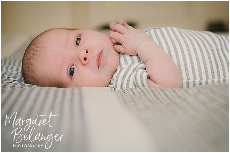 A baby boy lies on a big bed during his newborn photography session in Winchester, MA