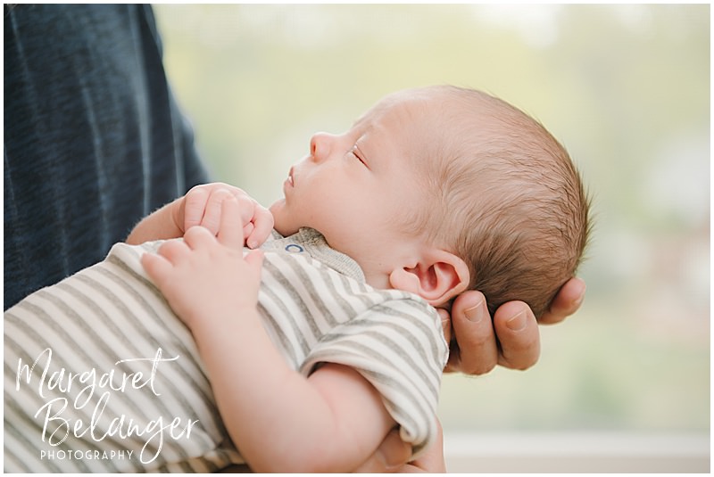Profile of a newborn baby boy in dad's hands at his newborn photo session in Winchester, MA