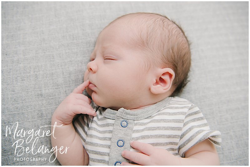 Sleeping baby looking thoughtful with his index finger at his mouth during his Winchester, MA newborn photo session