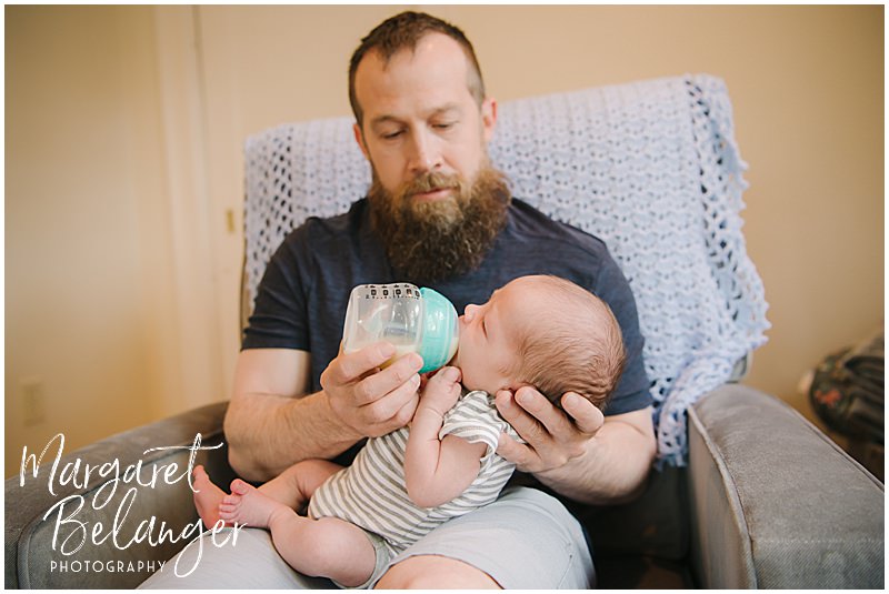 Dad feeding his newborn baby a bottle at a newborn photo session in Winchester, MA