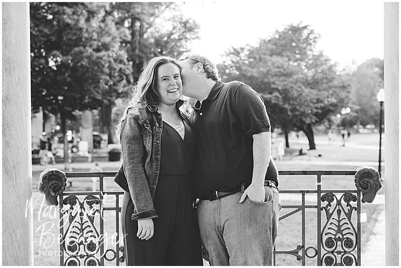A black and white photo of a man nuzzling his laughing fiancee in the Boston Common gazebo.