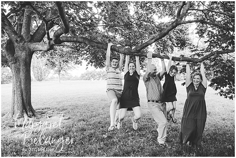 Black and white photo of a family of five all hanging from a tree branch in Larz Anderson Park in Brookline.