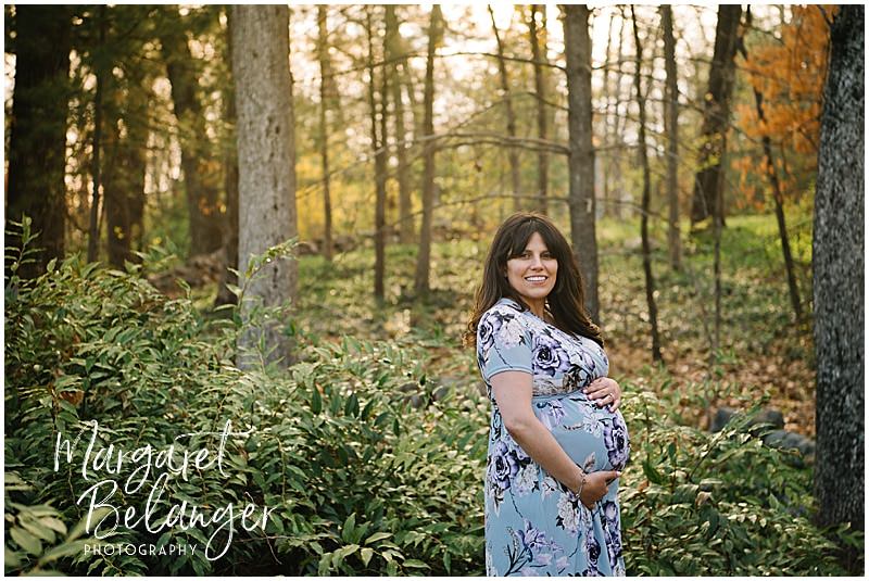 A mom-to-be cradles her pregnant belly among the trees during her Norfolk, MA maternity session.
