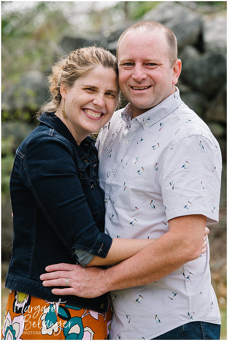 A man and a woman hug and pose for a portrait during a spring family photo session at Minute Man National Park in Concord.