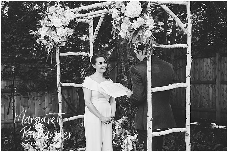 Black and white photo of a bride and groom exchanging vows during a backyard wedding in Winchester, MA.