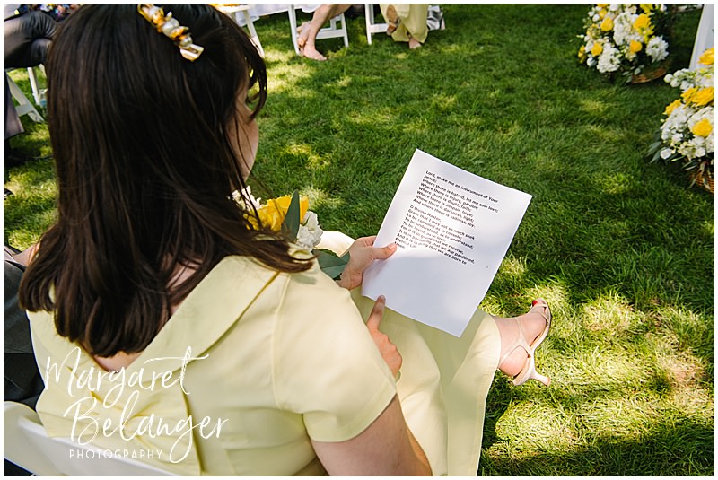 Guest reading a program during a backyard wedding in Winchester, MA.