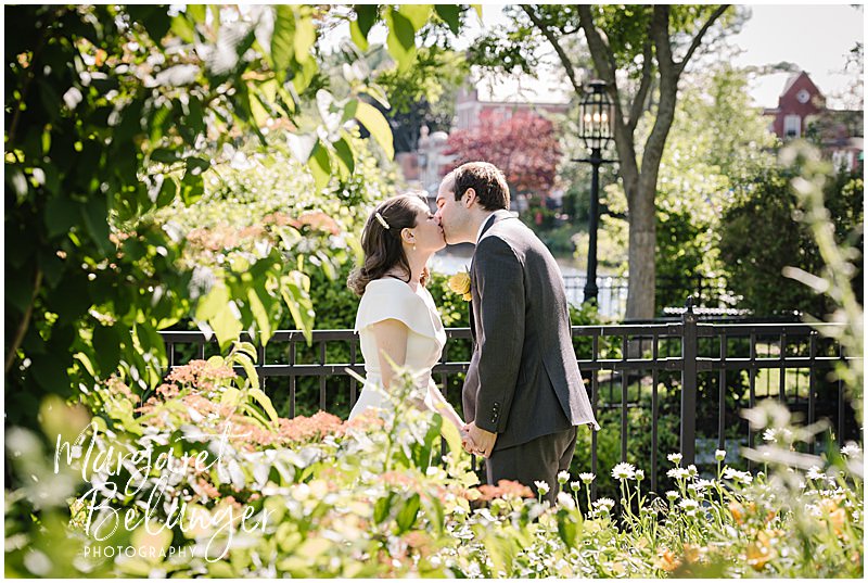 Bride and groom kiss by the pond in Winchester Center.