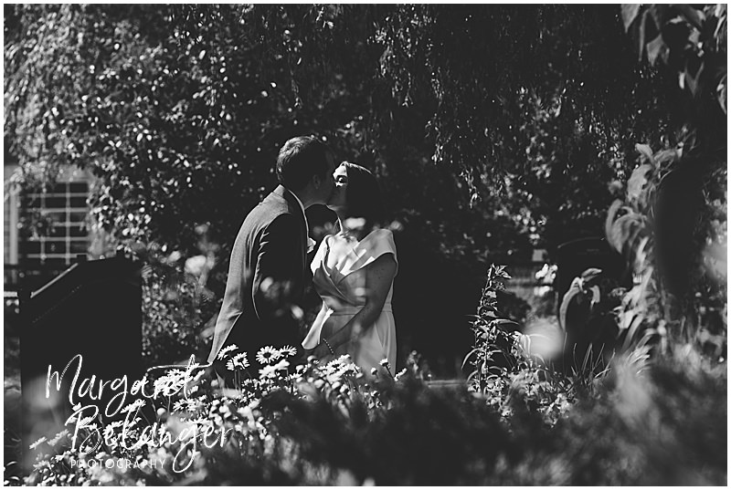 Black and white portrait of the bride and groom kissing by the pond in Winchester Center.