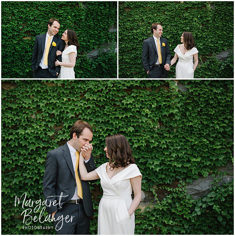Portrait of a bride and groom standing in front of a green vine-covered stone wall in Winchester Center.