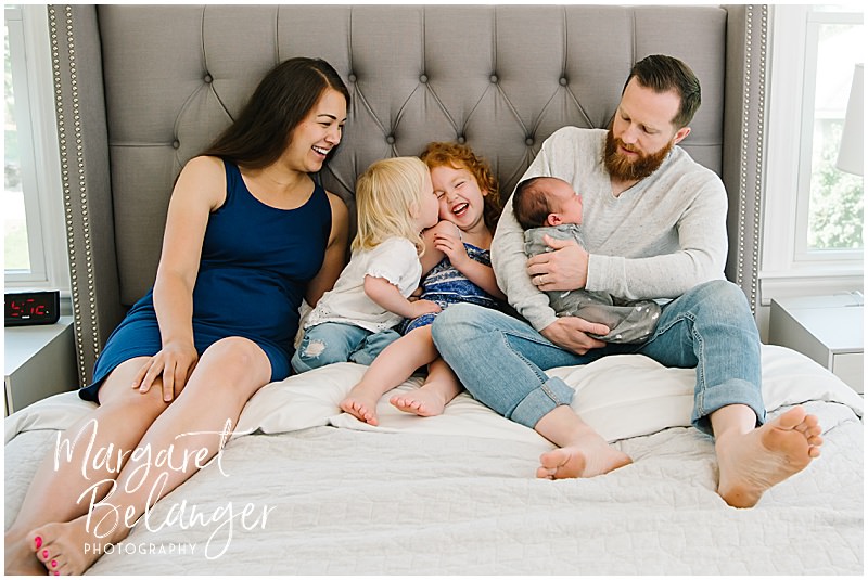 Family of five crowds onto the bed for a family portrait during a newborn session in Winchester, MA.
