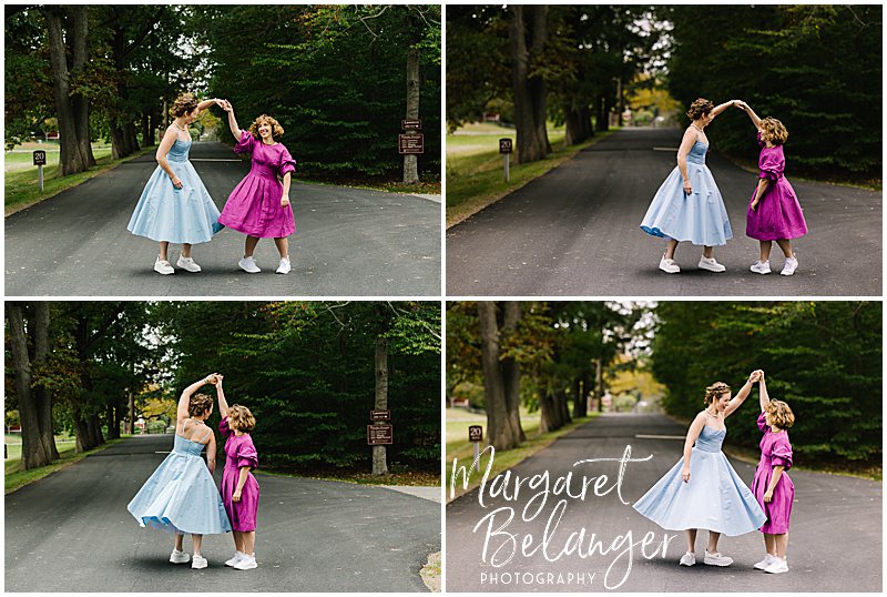 A bride in a blue dress dancing with a bride in a pink dress on a farm road.