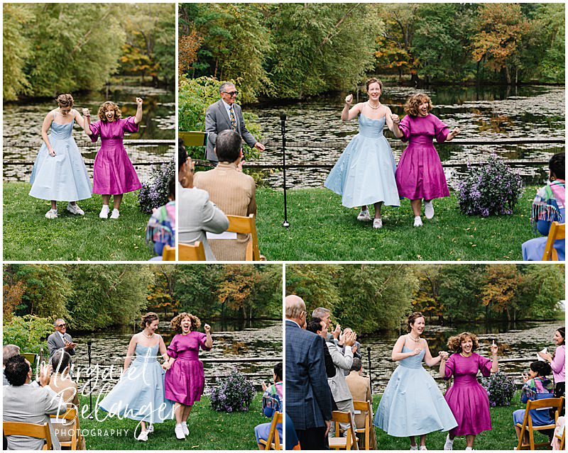 Two brides dance joyously back up the aisle at the end of their wedding ceremony.