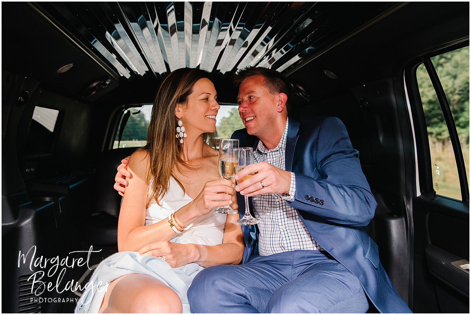 A bride and groom toasting with champagne inside a limousine.